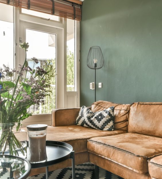 a living room with a brown leather couch and black and white patterned rug on the floor next to a glass coffee table