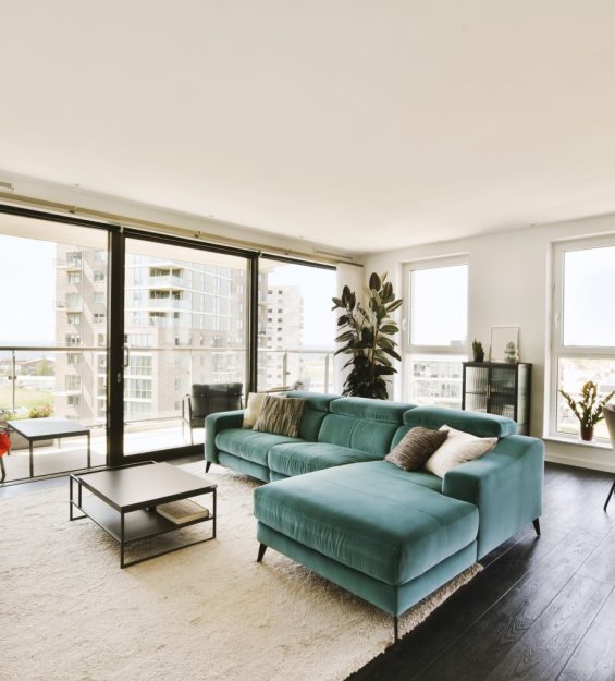 a living room with couches and flowers on the table in front of large windows looking out onto the street